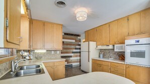 A kitchen with wooden cabinets, a stainless steel sink, and a built-in oven.