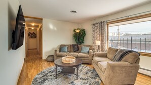 A living room with a sofa, a coffee table, and a TV mounted on the wall.