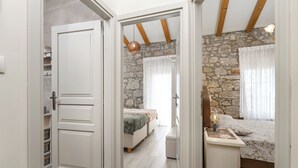 Un dormitorio con pared de piedra, cama con colcha floral, mesita de noche con lámpara y un armario.