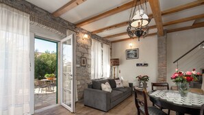Una sala de estar acogedora con un sofá gris, piso de madera y una mesa de comedor con mantel de encaje.