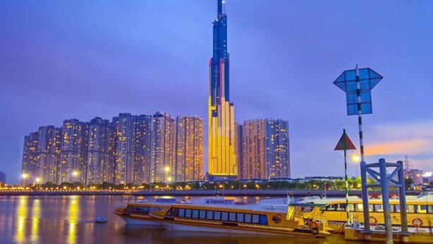 A cityscape with a prominent skyscraper, a river, and a yellow bus.