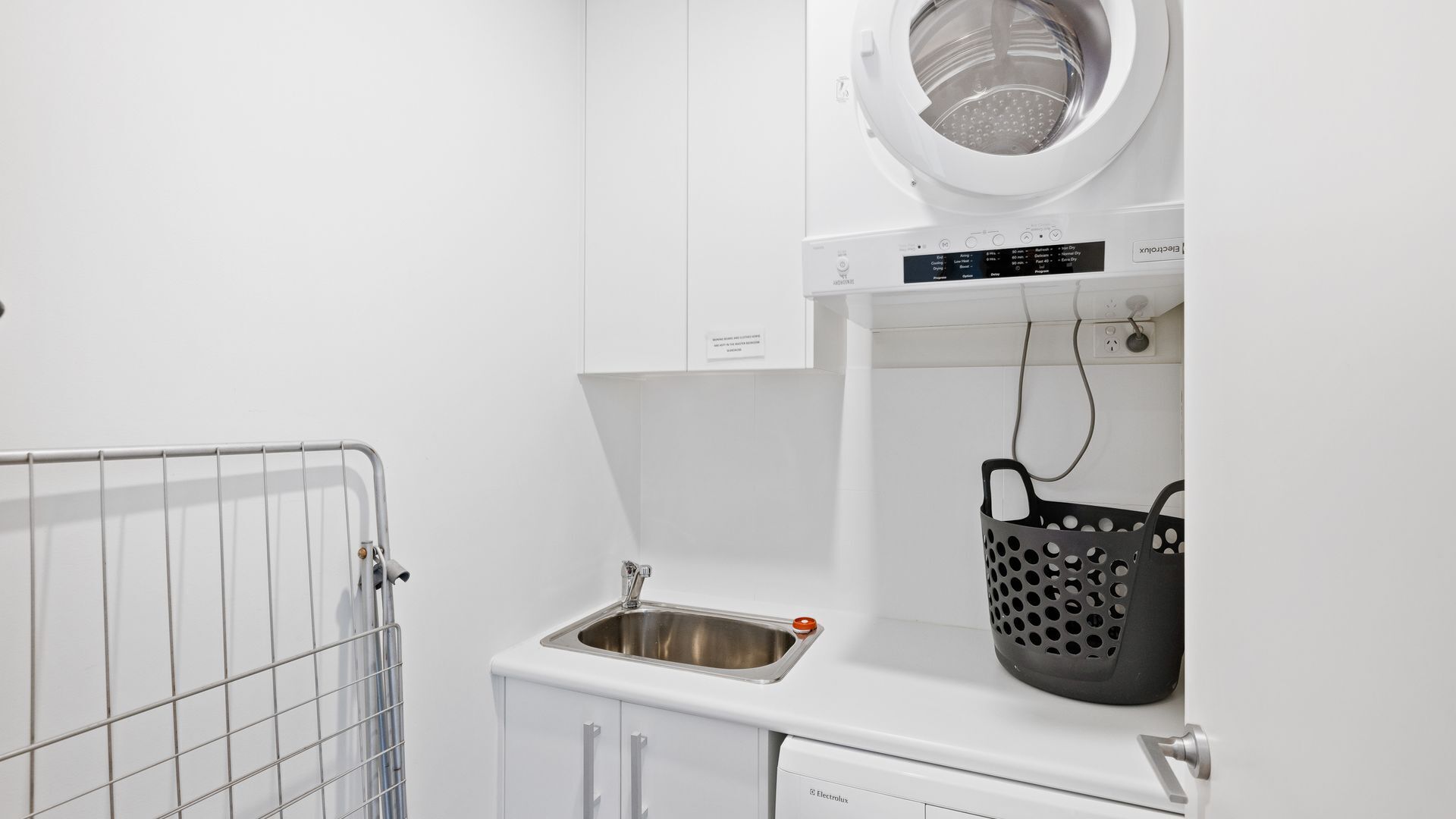Un espacio de lavandería con lavadora, lavabo y tendedero.