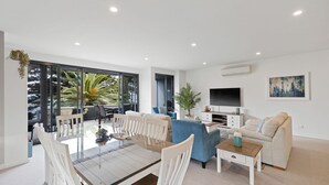 A modern living room with a glass dining table, sofas, and a TV. - Beachfront on the Esplanade (Cowes)