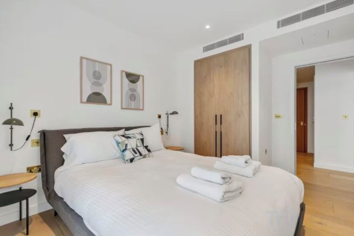 A bedroom with a bed, bedside tables, wall-mounted lamps, and a wardrobe.