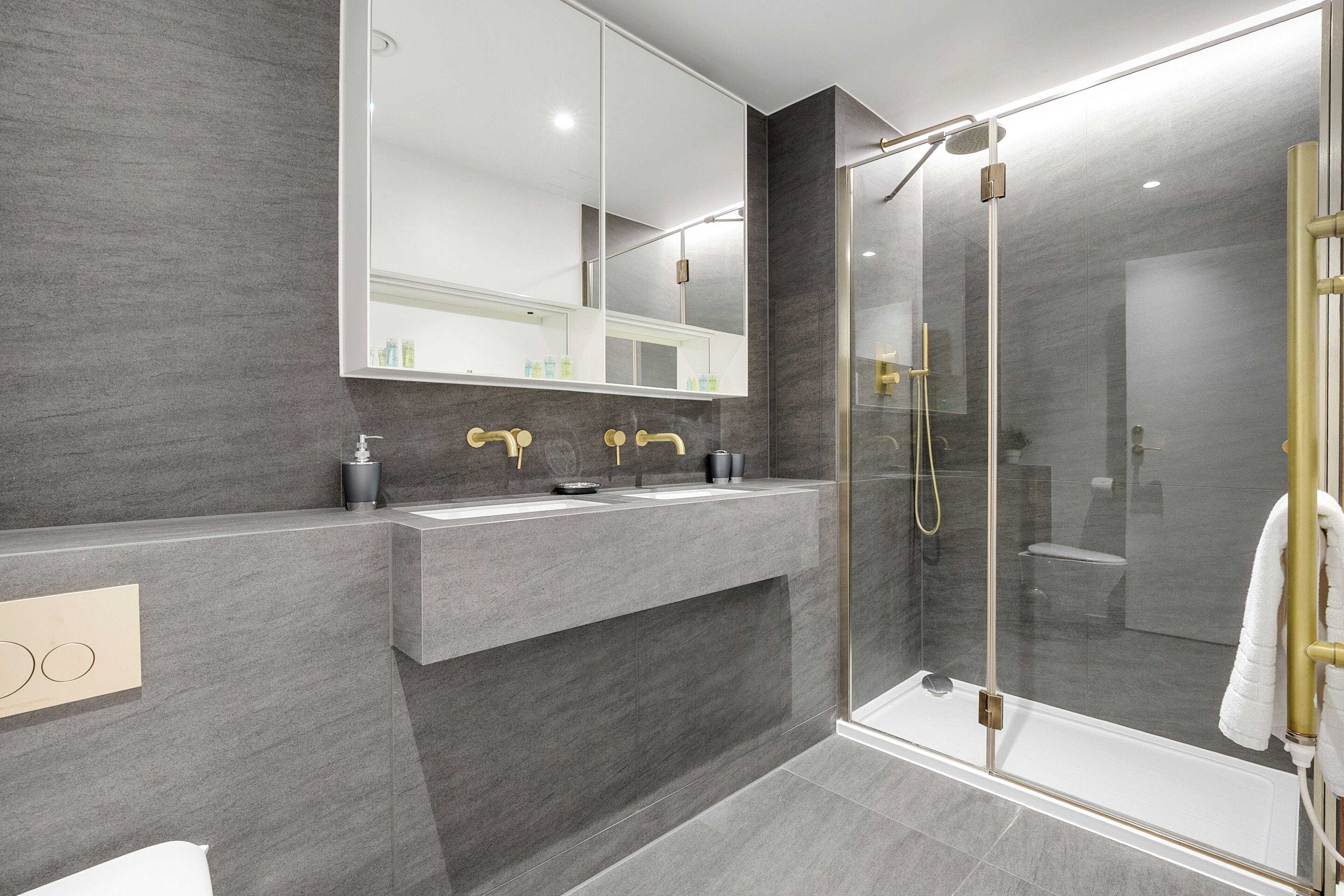 A modern bathroom with a large mirror, two sinks, and a glass-enclosed shower area.
