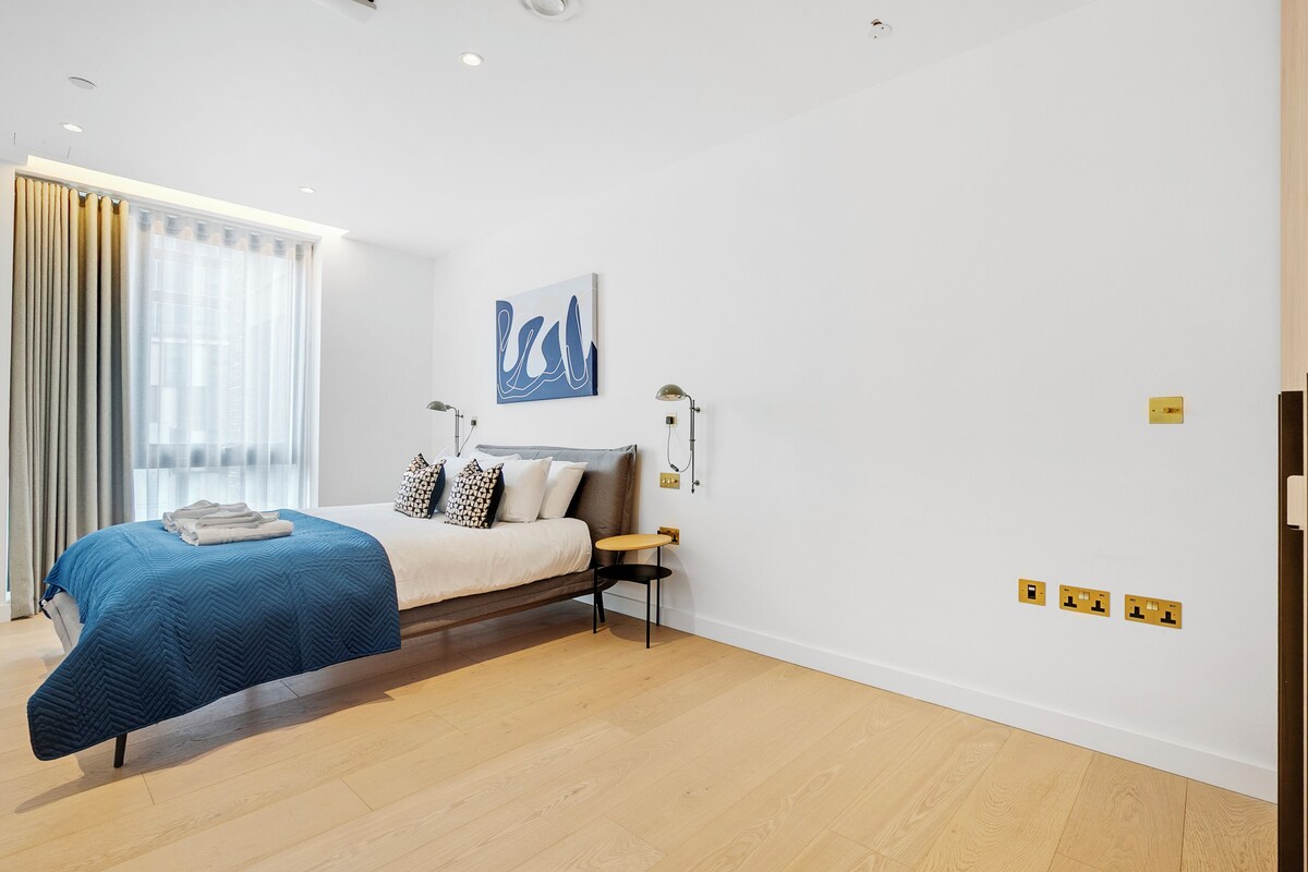 A modern bedroom with a bed, bedside table, and a wall-mounted artwork.