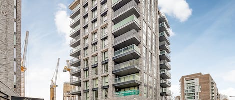 A multi-story building with balconies, a construction crane, and a sign for premium rental apartments.