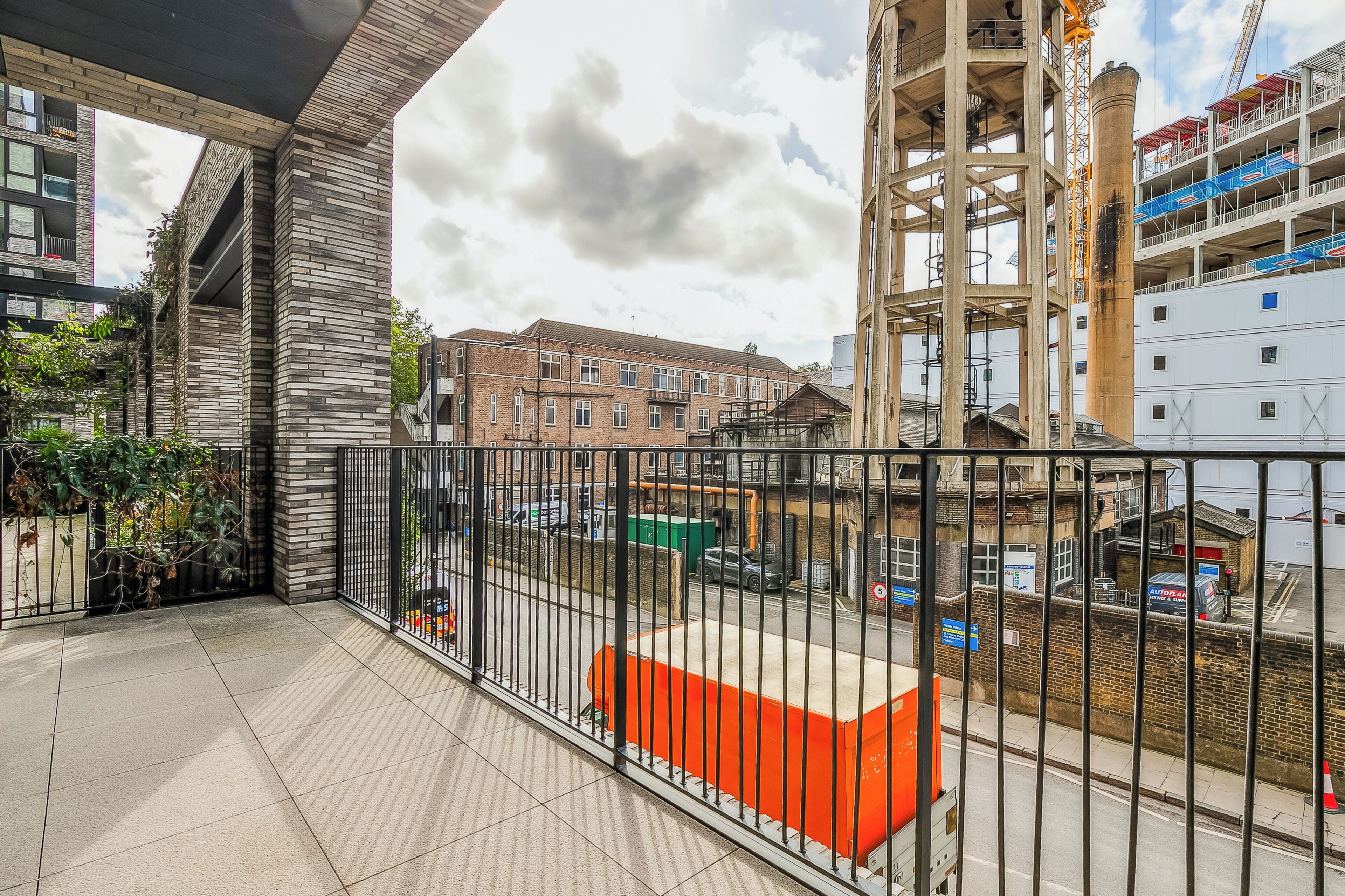 A balcony with a view of a construction site and a brick building.
