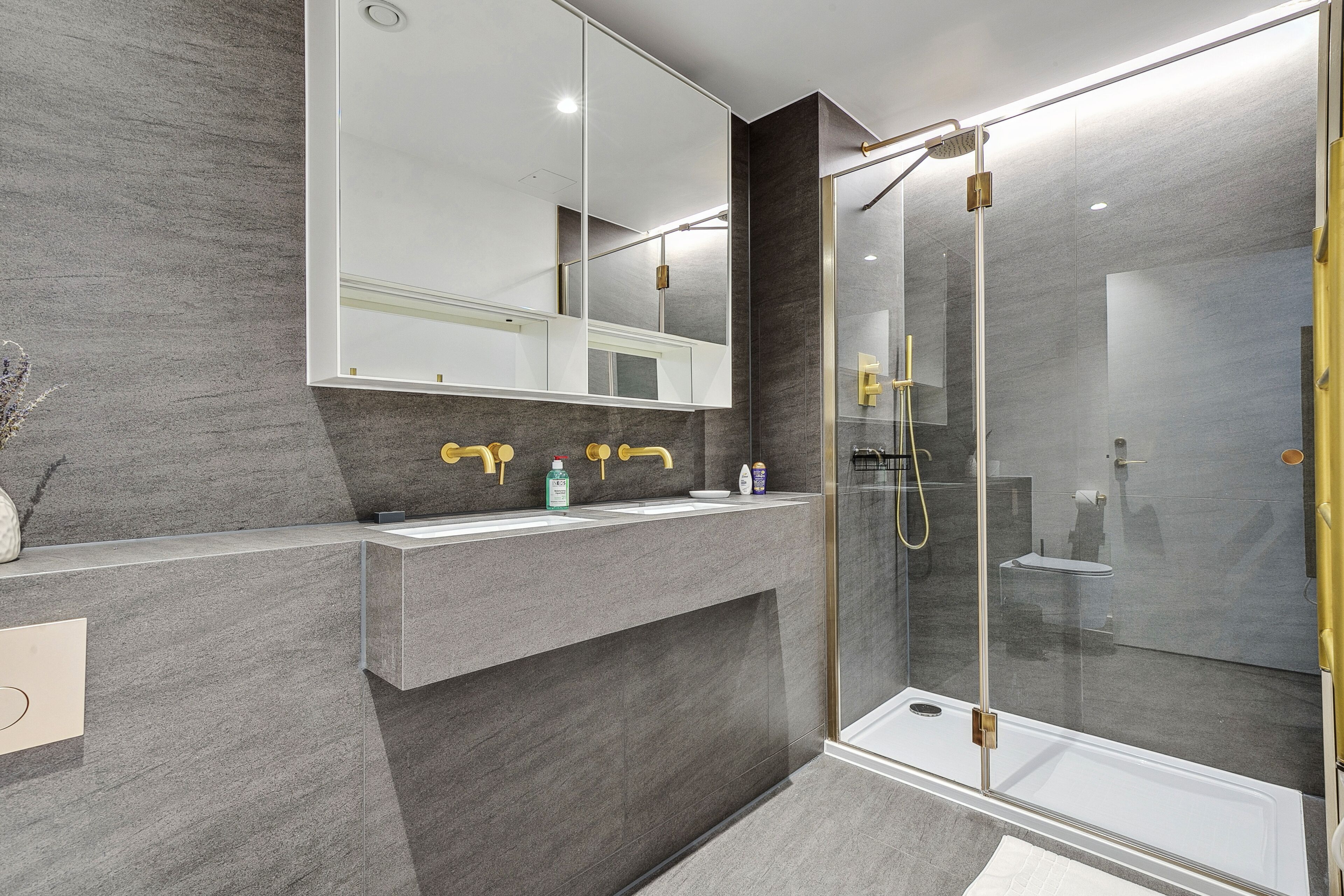 Un bagno moderno con doccia vetrata, uno specchio grande e un lavabo doppio.