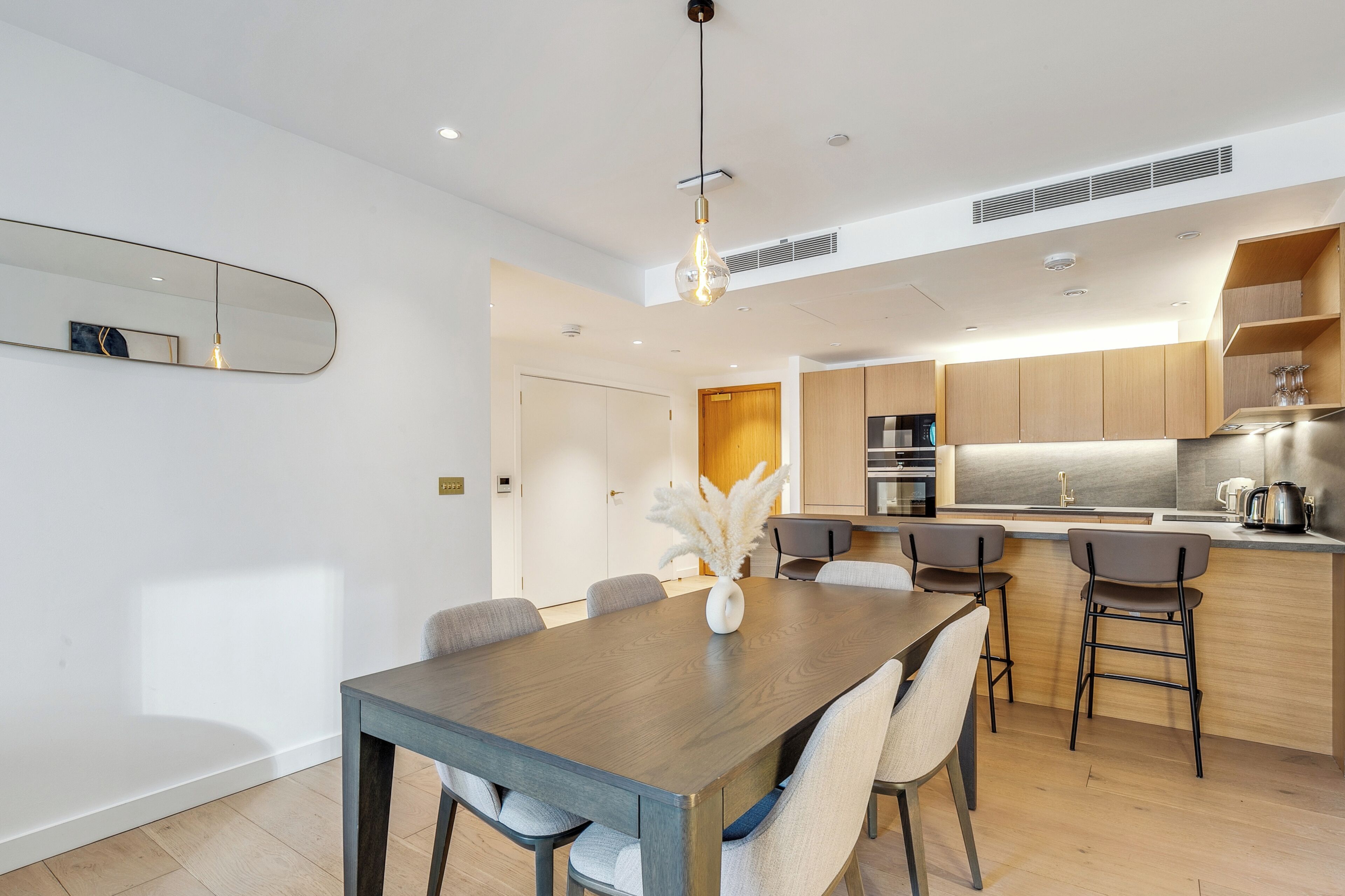 A modern kitchen with wooden cabinets, a central island, and a dining area with a wooden table and chairs.