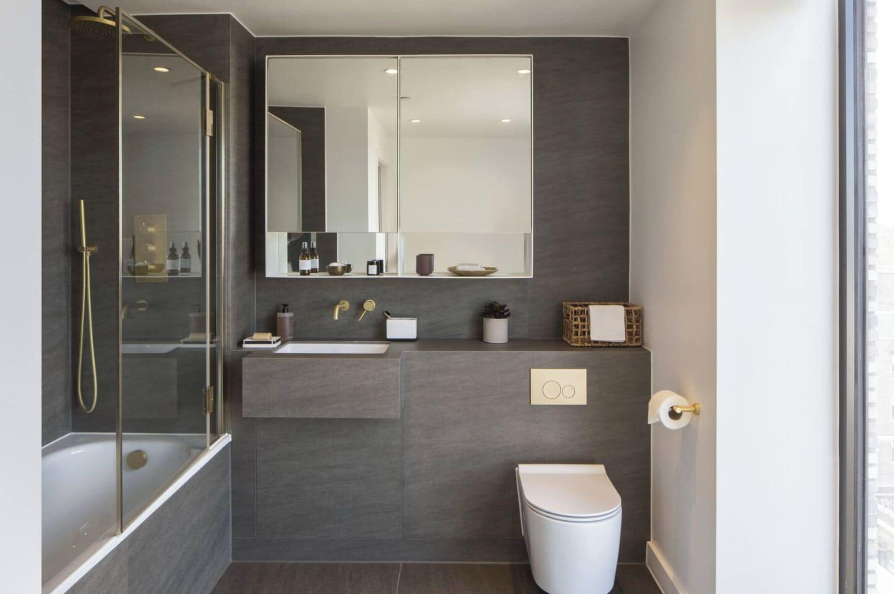 A modern bathroom with a glass-enclosed shower, a white sink, and a toilet.