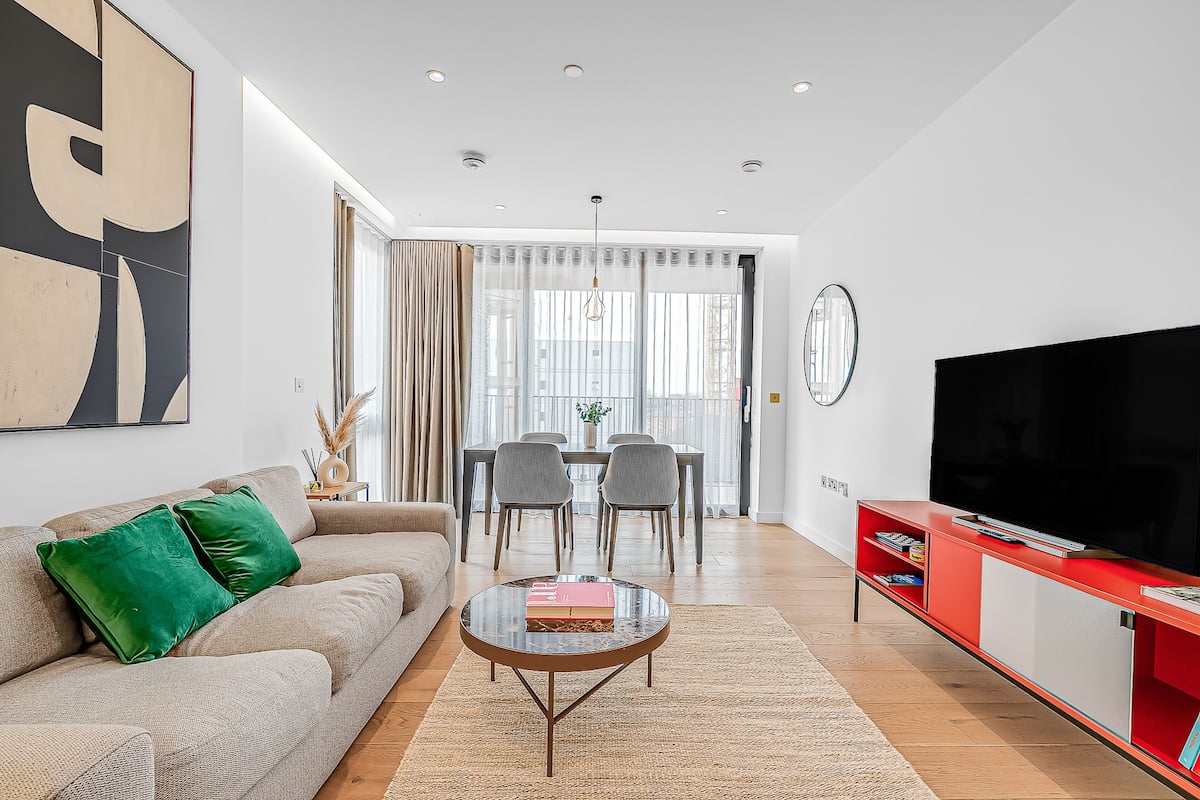 Una sala moderna con sofá, mesa de centro, mueble para televisión y comedor.
