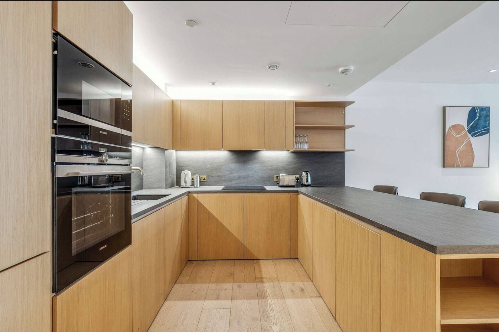 A modern kitchen with wooden cabinets, a stainless steel oven, a sink, and a countertop.