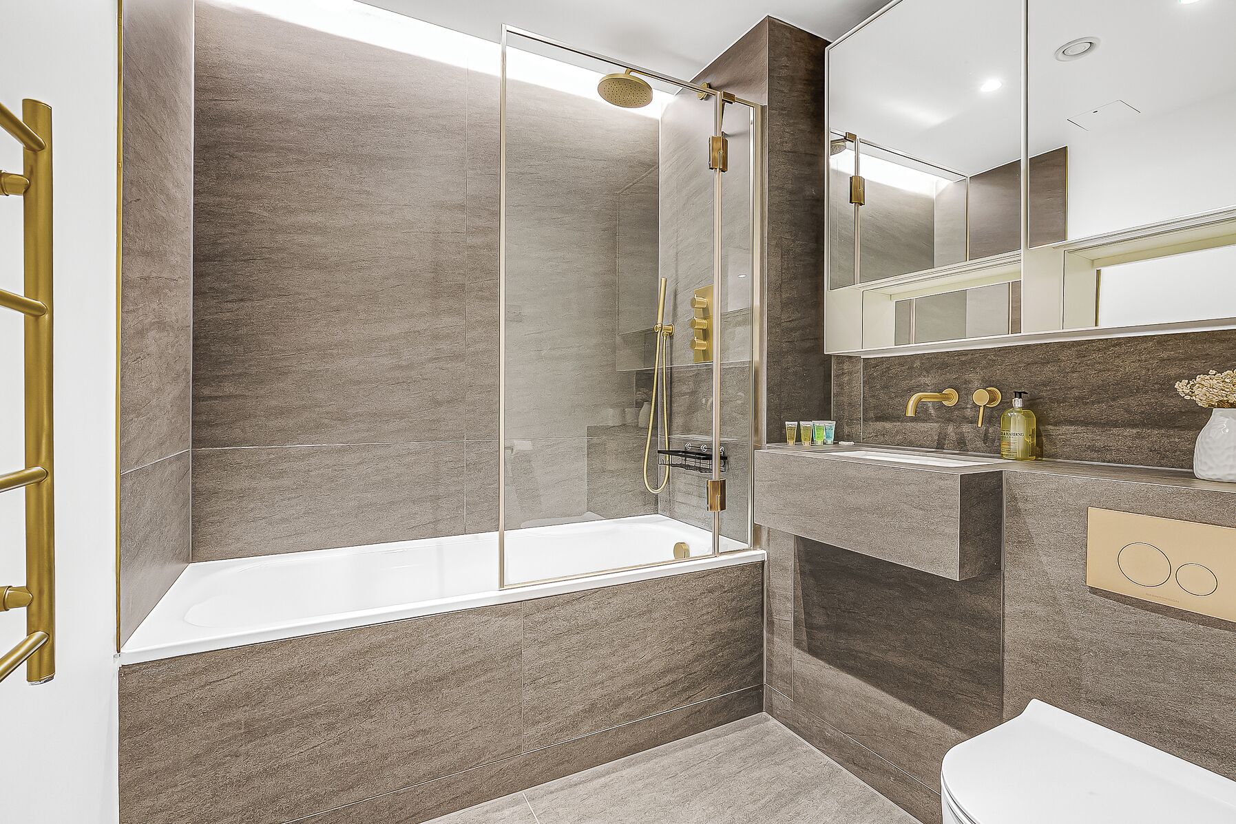 A modern bathroom with a glass-enclosed shower, a white bathtub, and a vanity with a mirror.