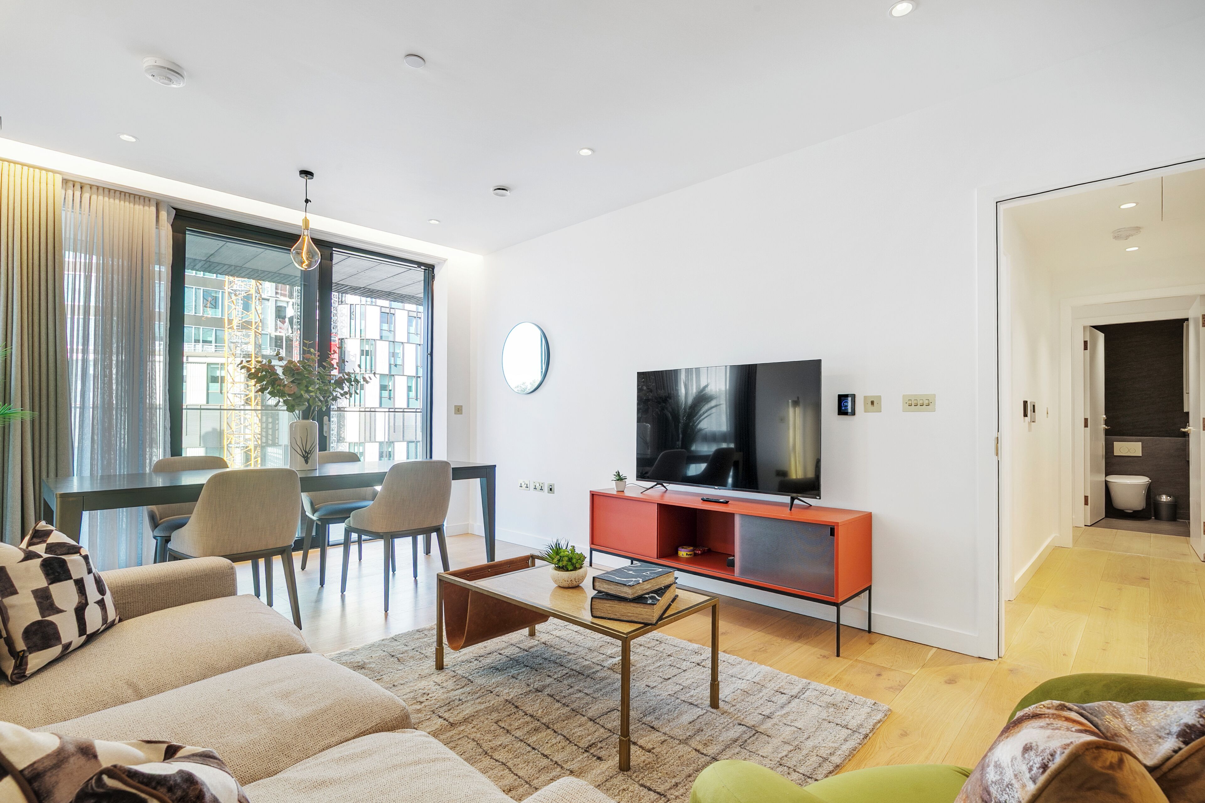A modern living room with a sofa, coffee table, TV, and dining area.
