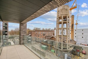 A modern building with a glass balcony overlooking a construction site and residential buildings. - StayCozy Apartments in Kings Cross (London)