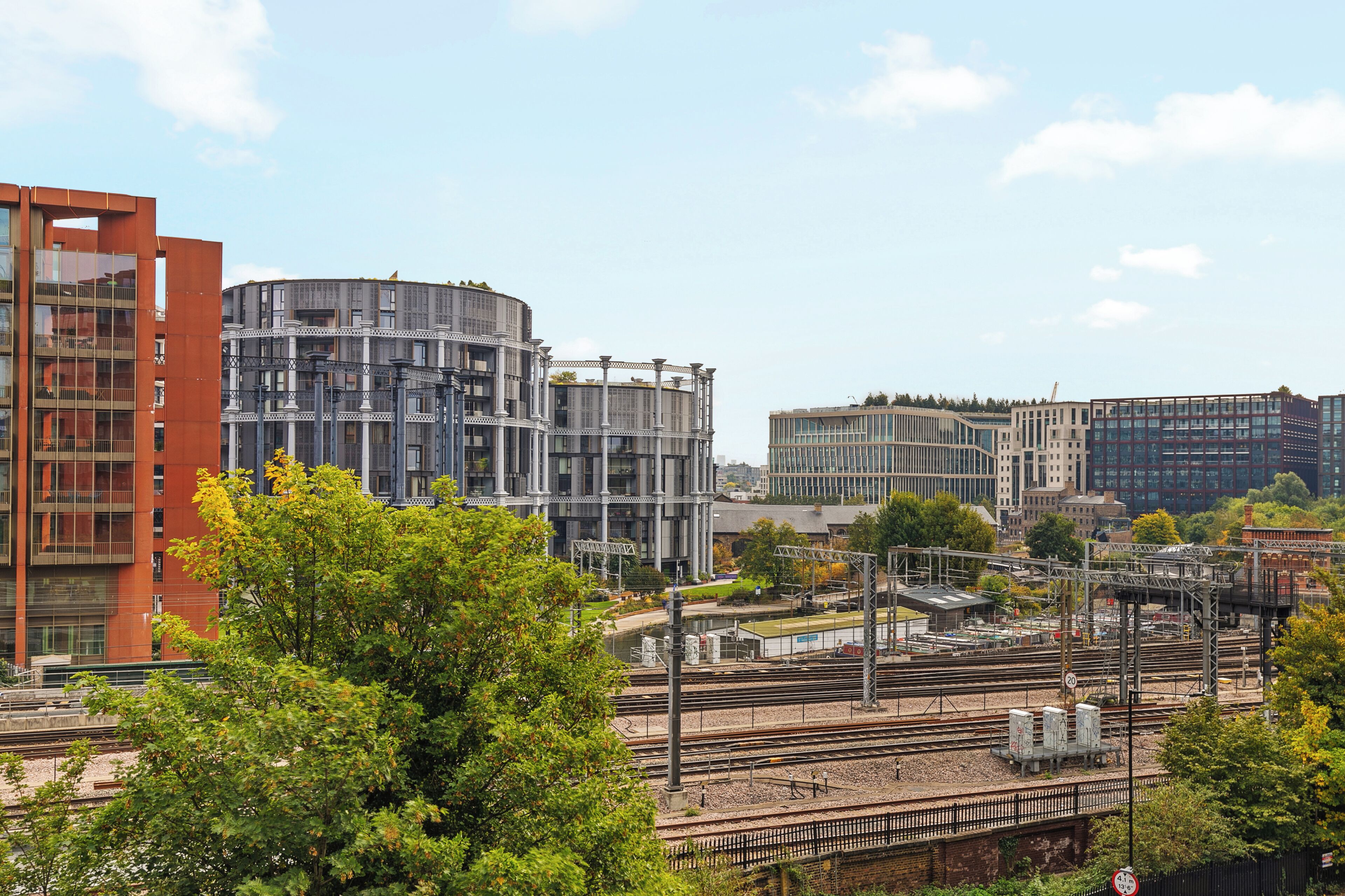 A modern urban landscape with multiple high-rise buildings, a railway station, and greenery.
