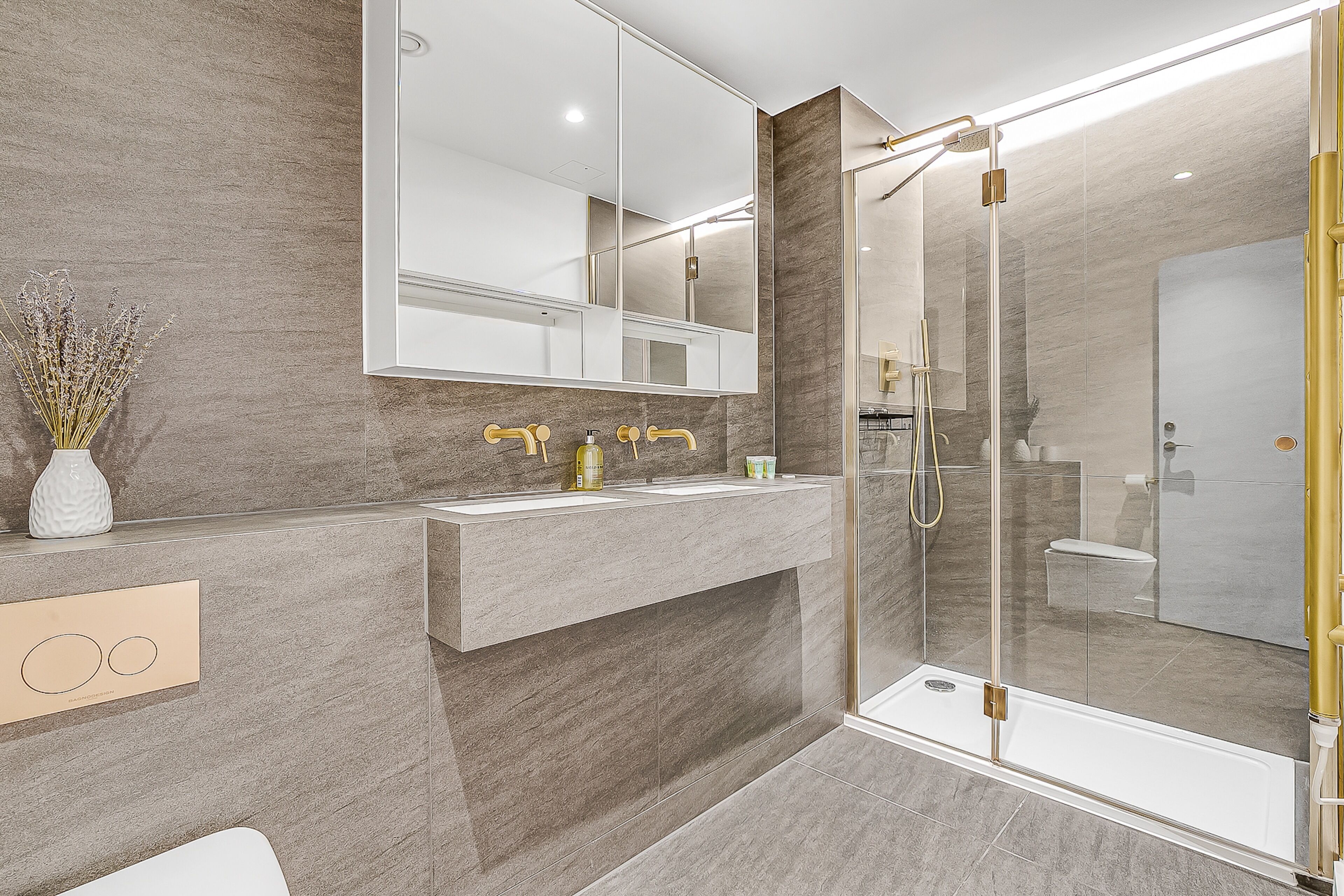 A modern bathroom with a glass-enclosed shower, a large mirror, and a vanity with two sinks.