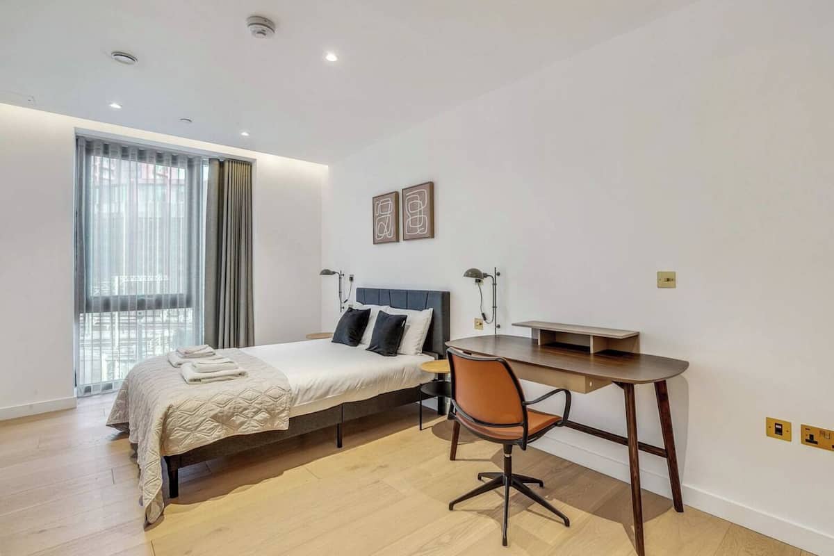 Un dormitorio con una cama, un escritorio y una silla.