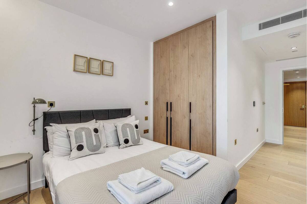 Un dormitorio con cama, armario, mesita de noche y lámpara.
