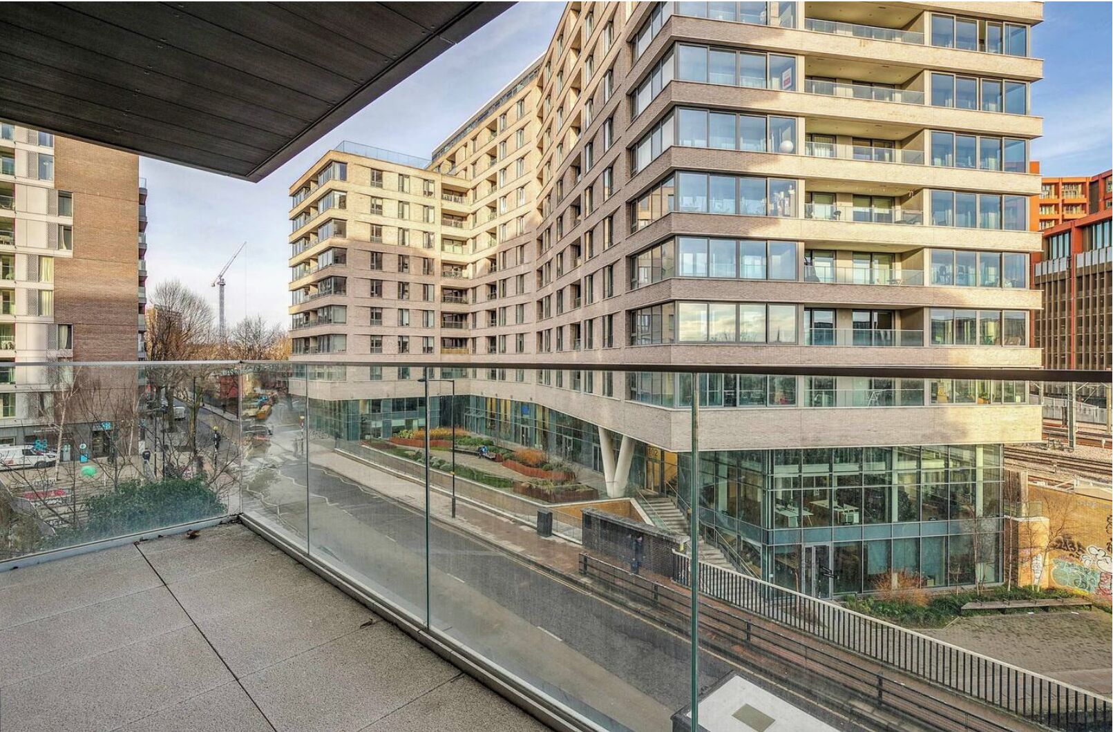 Un edificio moderno de varios pisos con fachada de vidrio, un patio interior y vistas del área urbana circundante.