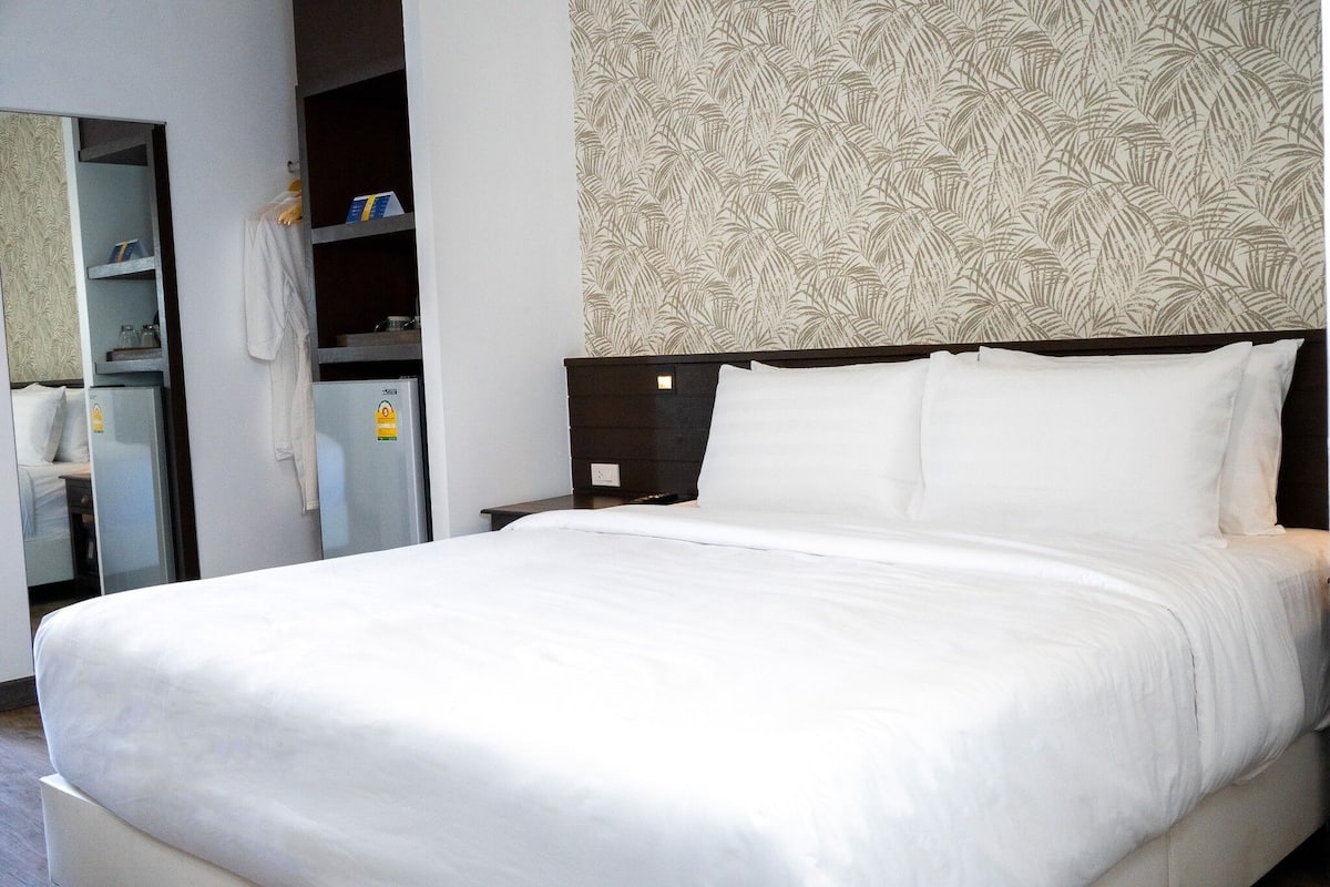 Een hotelkamer met een groot bed, een kledingkast en een spiegel.