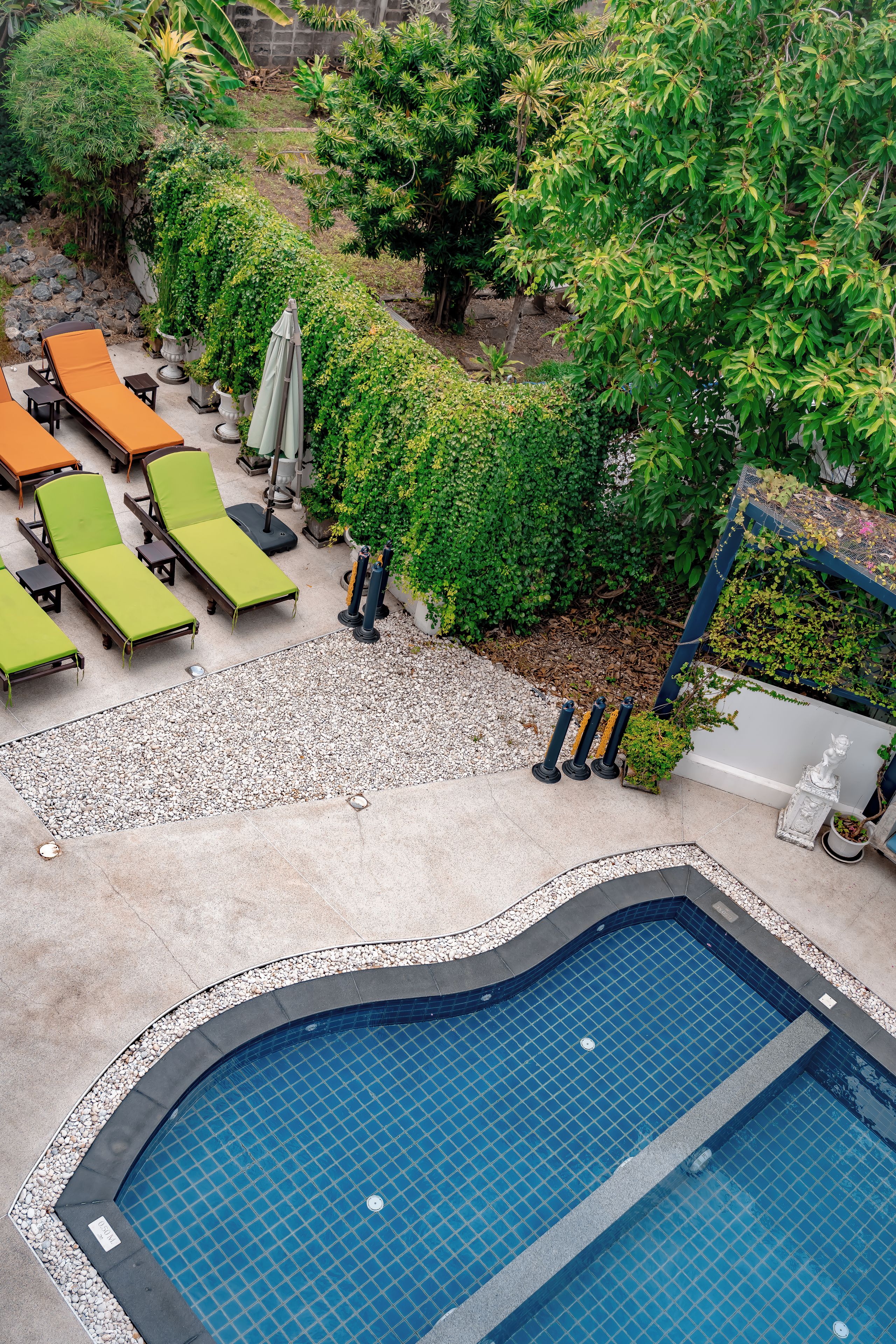 A pool area with lounge chairs, a swimming pool, and surrounding greenery.