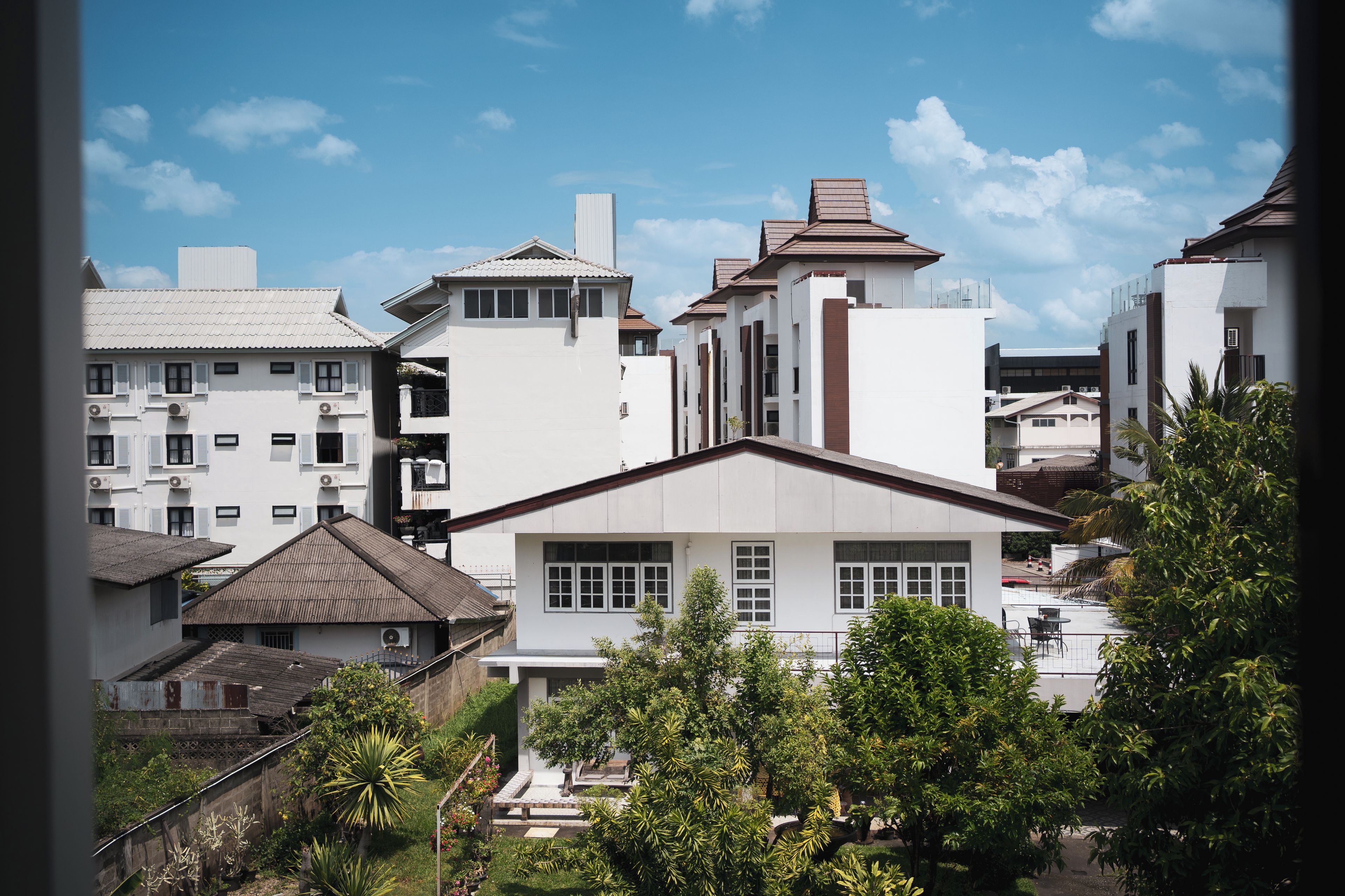 A residential area with modern buildings, a well-maintained garden, and a clear sky.