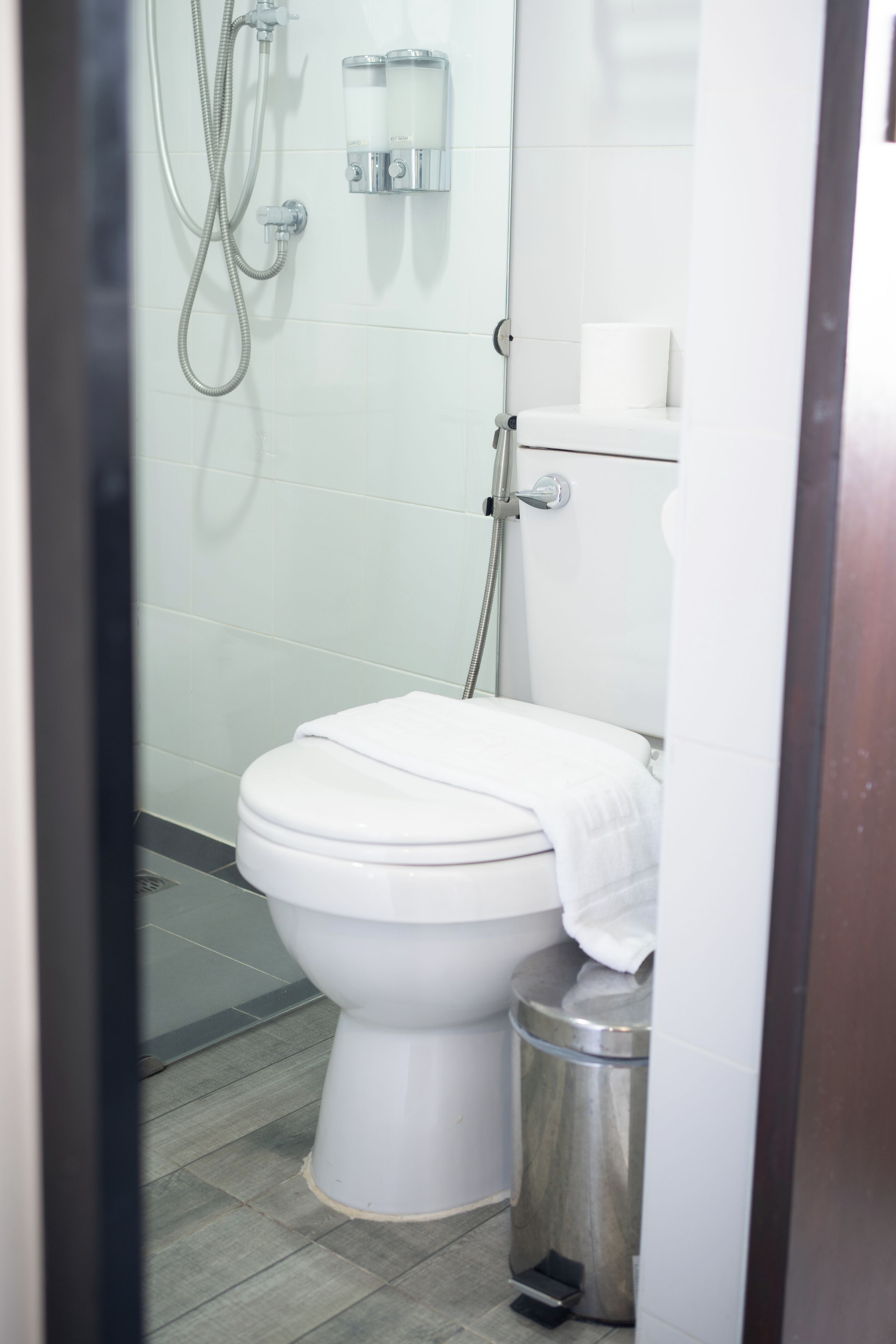Un baño con inodoro, ducha y cubo de basura.