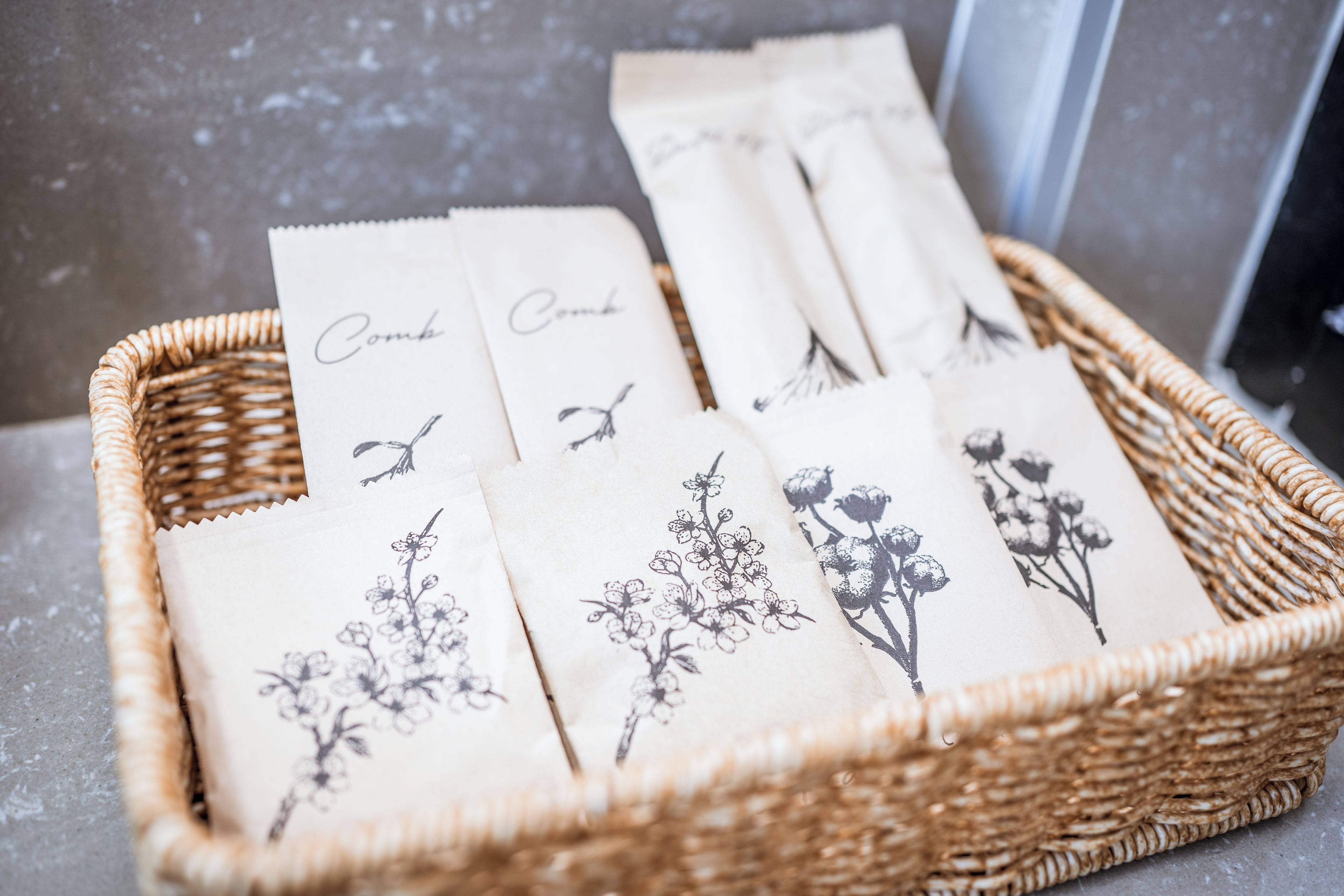 Een rieten mand met verschillende witte kaartjes met bloemmotieven en de tekst 'Comb'.