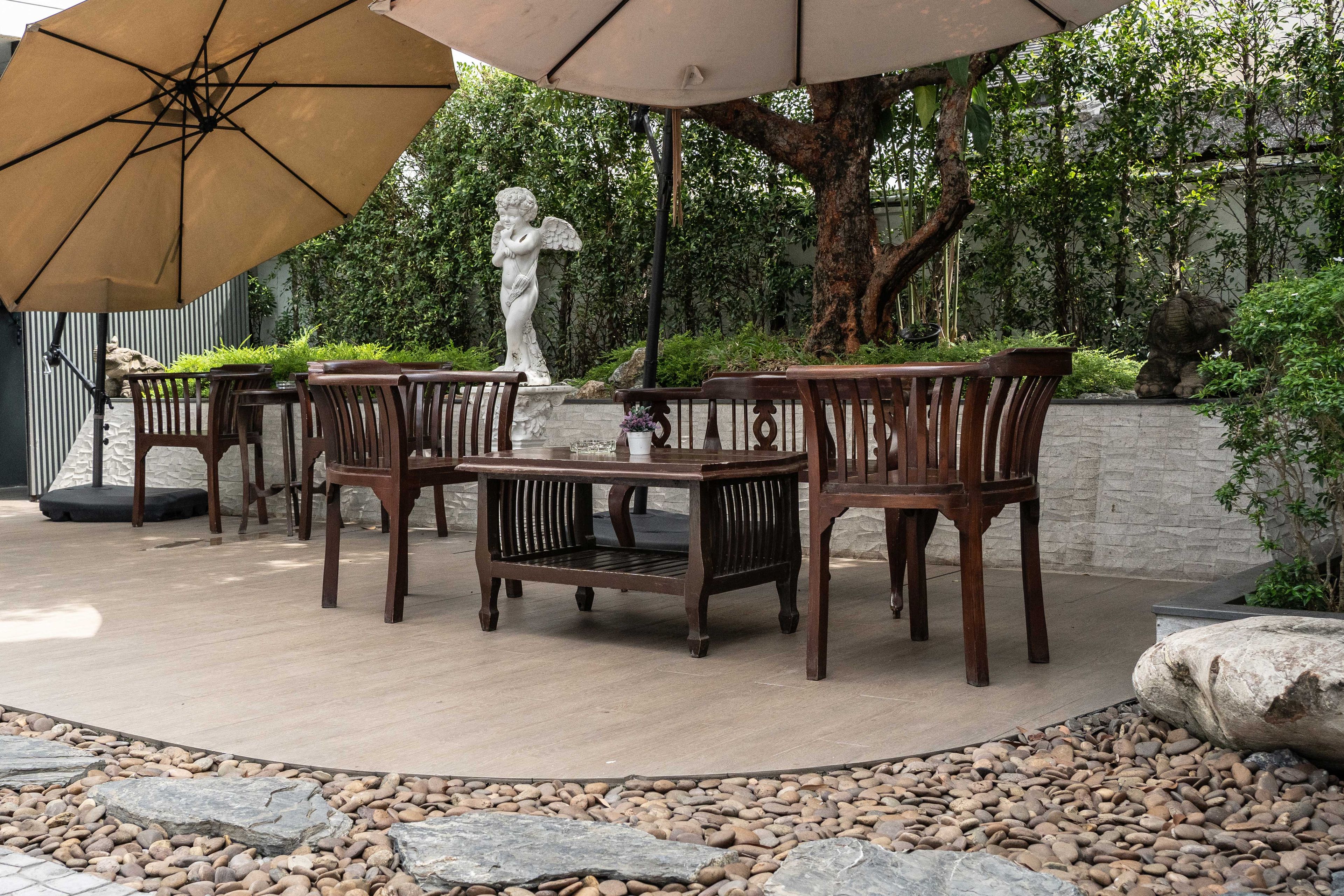 Une terrasse extérieure avec une table ronde, quatre chaises et une statue.