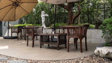 Une terrasse extérieure avec une table ronde, quatre chaises et une statue.