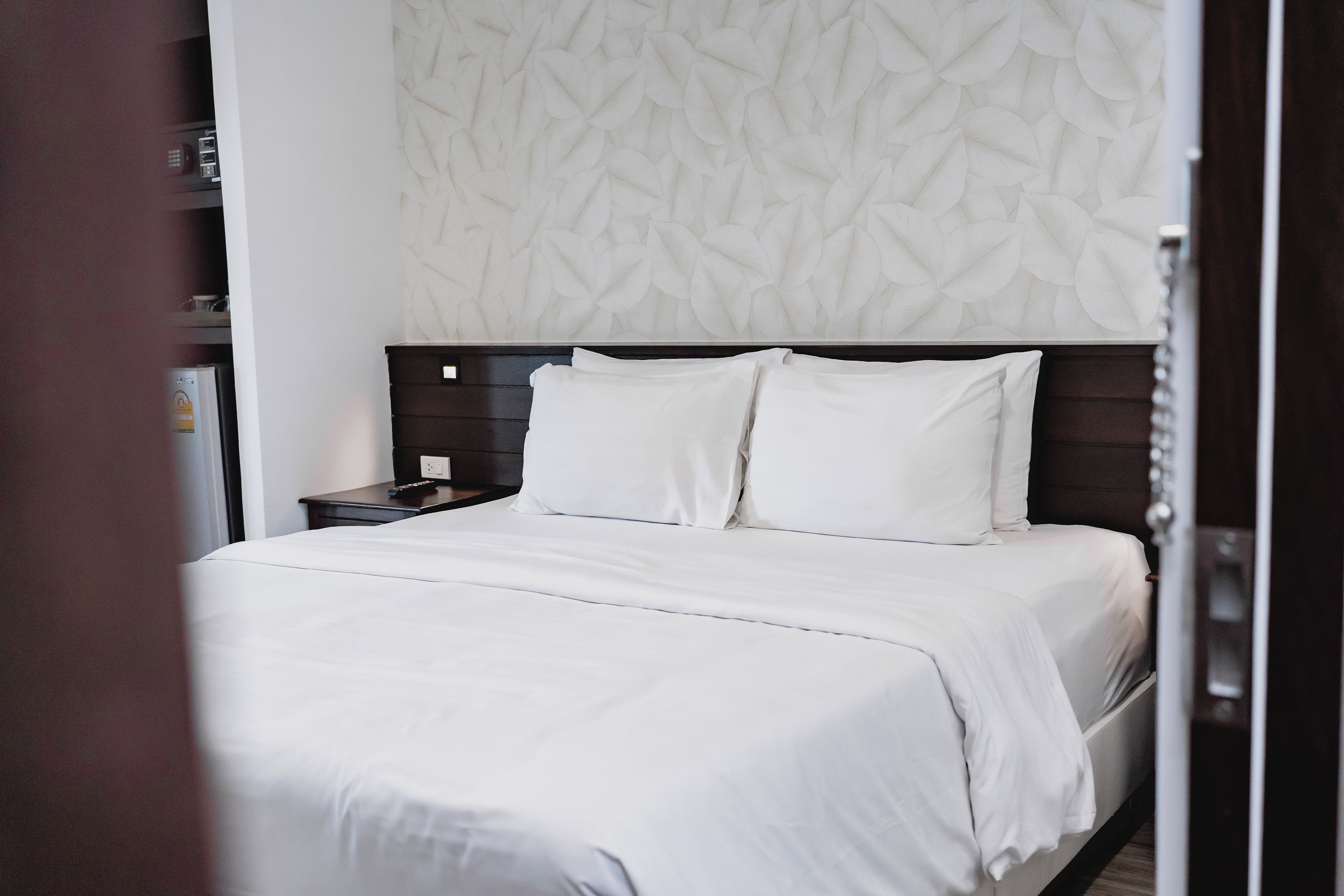 A neatly made bed with white linens in a hotel room.