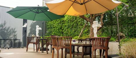 Un patio al aire libre con muebles de madera, un camino de piedra y una estatua.