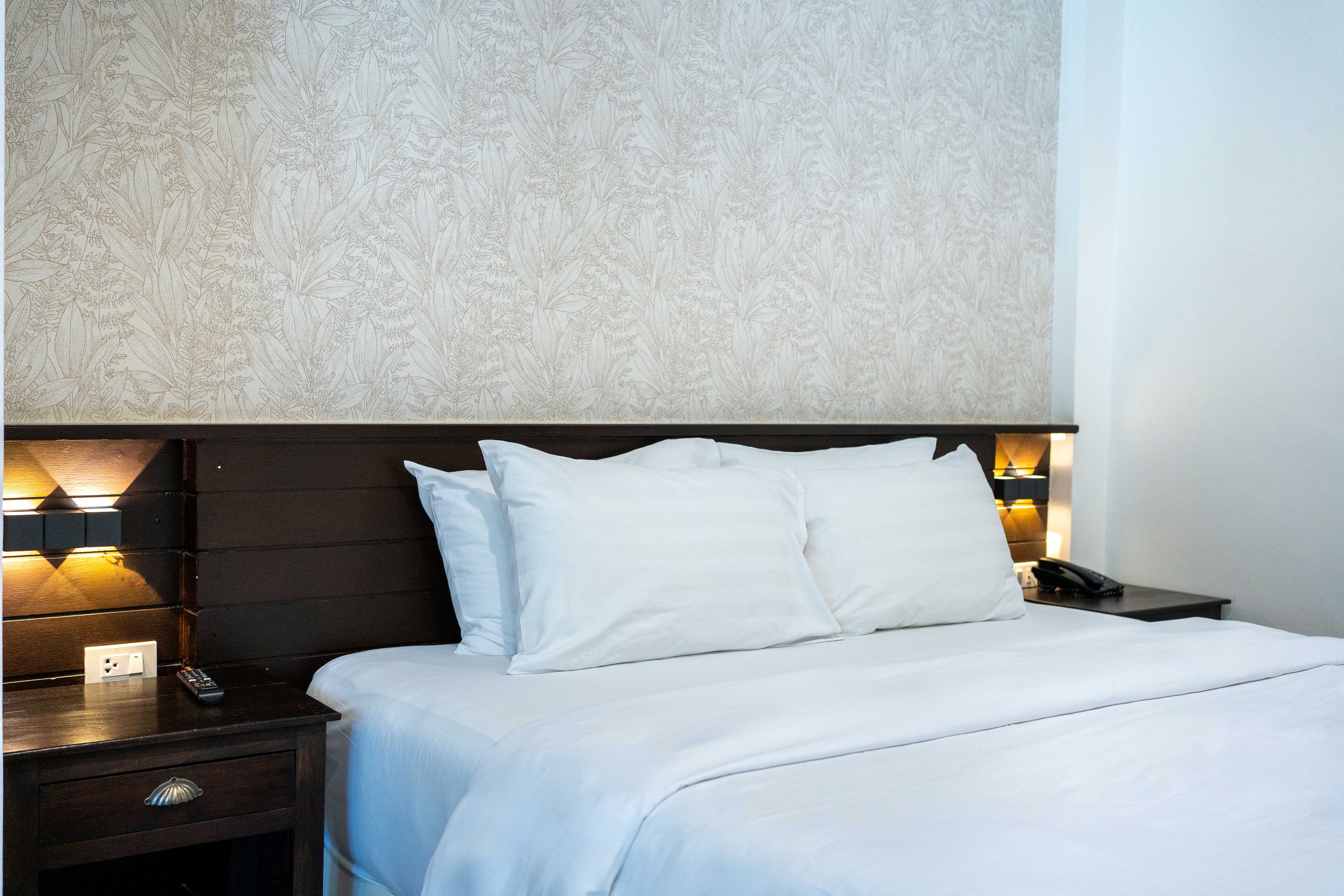 Una habitación de hotel con cama, mesitas de noche y una pared con estampado floral.