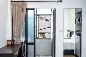 Ein Hotelzimmer mit Balkon, einem Bett, einem Kleiderschrank und einem kleinen Tisch.