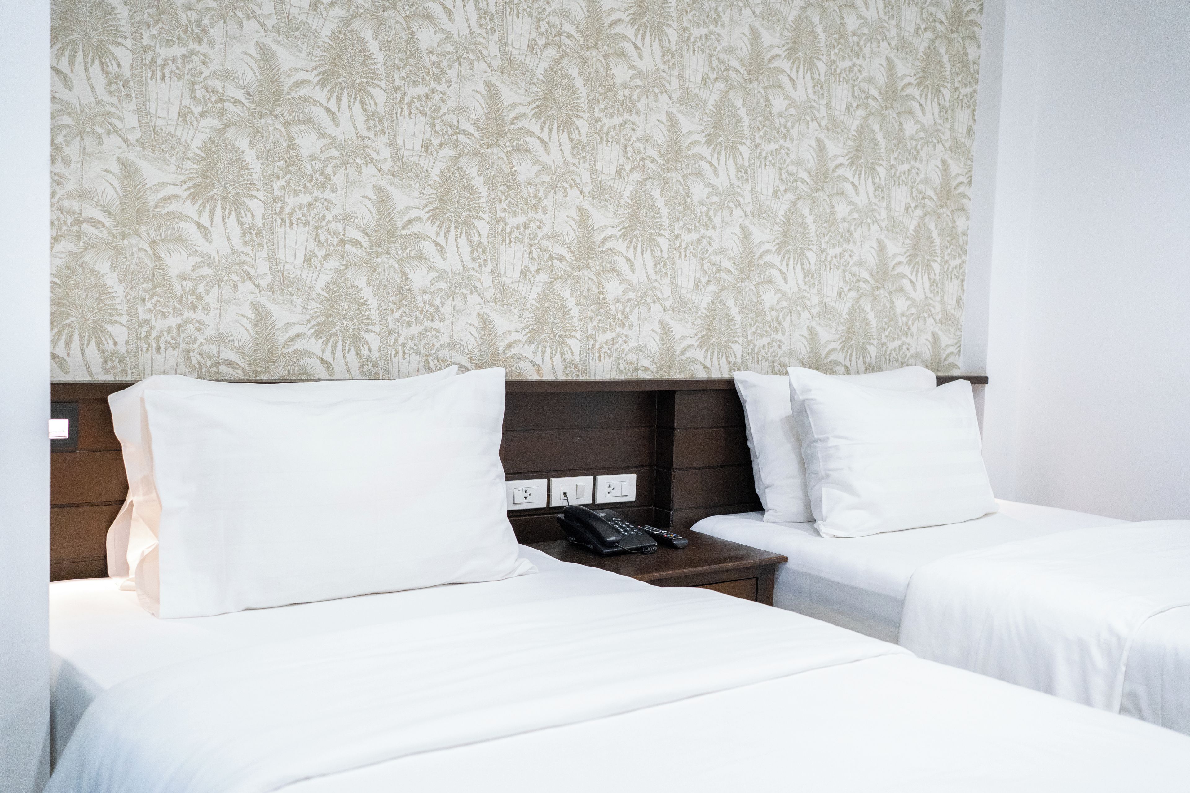 Habitación de hotel con dos camas, una mesita de noche y un teléfono.