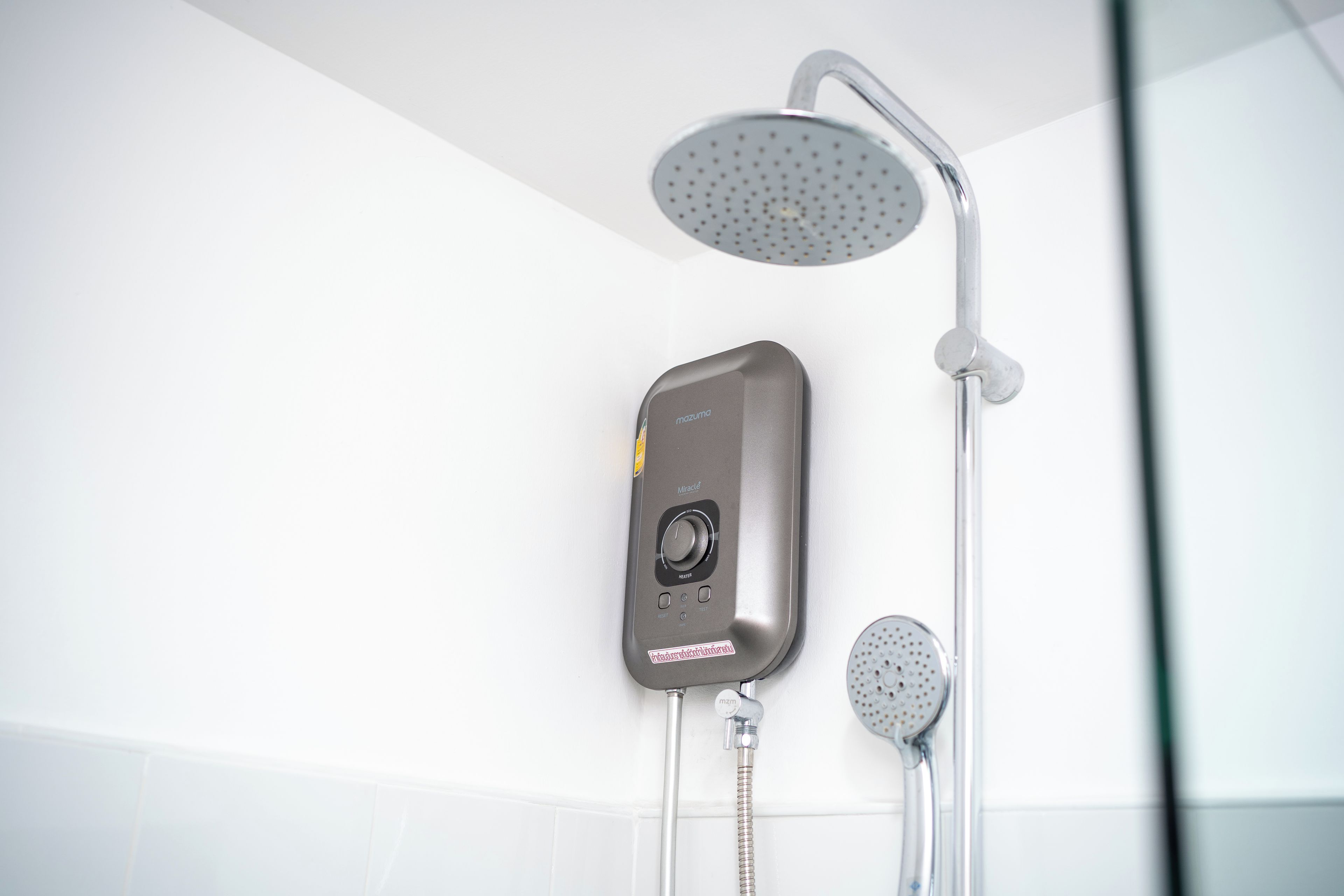 Une douche moderne dotée d’un pommeau de douche à main et d’un panneau de commande fixé au mur.