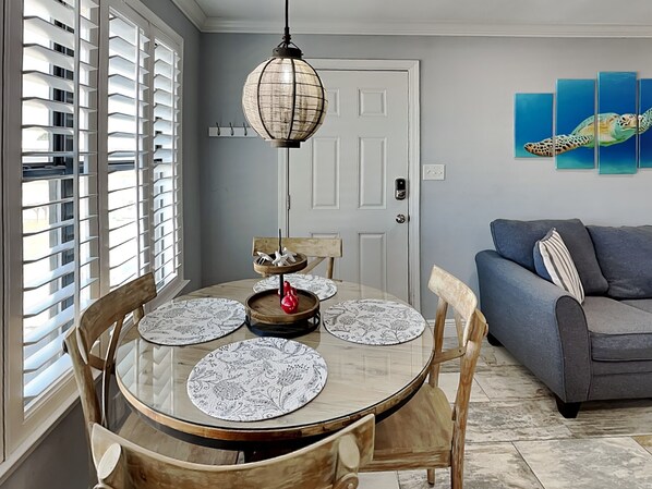A dining area with a round table, chairs, and a hanging light fixture.