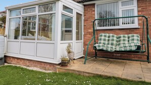 A house with a conservatory, a brick exterior, a window with blinds, a green swing, and a small garden. - Seaside Cottage (Scarborough)