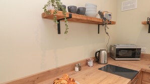 A kitchen with wooden countertops, a microwave, a kettle, and a plate of pastries. - Seaside Cottage (Scarborough)
