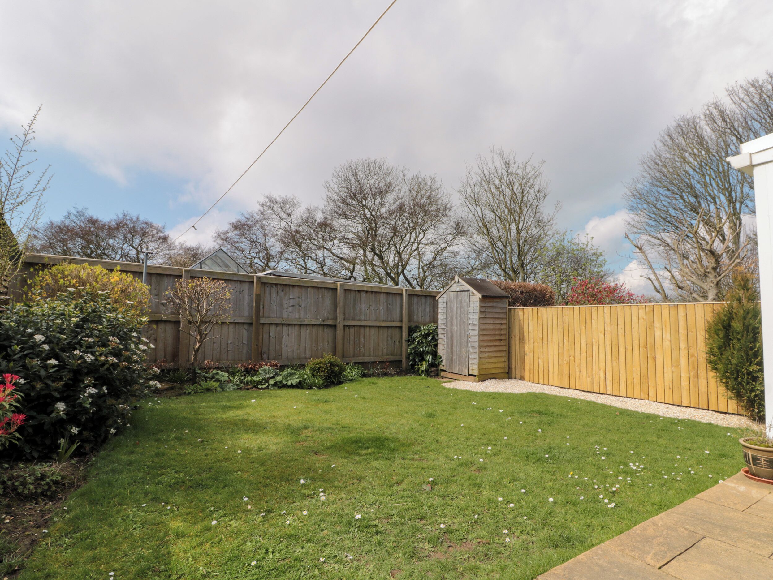 A backyard with a wooden fence, a shed, and a lawn.