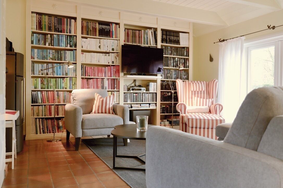 Una sala de estar con un sofá, sillones, una mesa de centro y una estantería llena de libros.