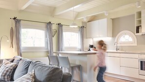 Een moderne keuken met witte kastjes, een centraal eiland en een eethoek met stoelen.