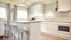Een moderne keuken met witte kasten, een centraal eiland en een inbouwoven.