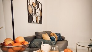 Ein Esstisch mit Frühstücksgebäck, Obst in einer Schüssel, einer Orangensaftflasche und einem Croissant.