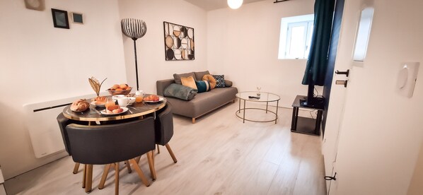 A modern living room with a dining area, a grey sofa, a coffee table, and a floor lamp. - L'art Déco 3 Wifi,netflix,disney+coeur de Bastide (Villefranche-de-Rouergue)