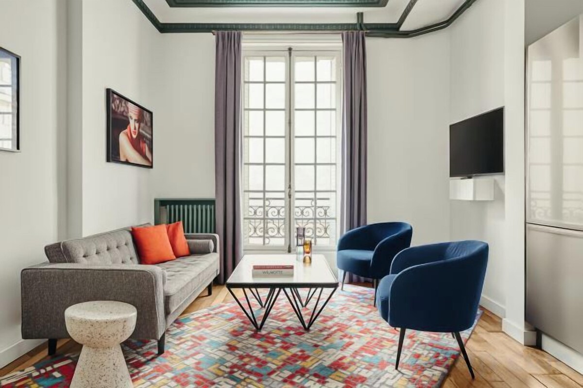 Een moderne woonkamer met een bank, stoelen, een salontafel en een kamerbreed tapijt.