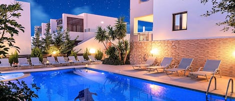 A swimming pool with lounge chairs and a dolphin sculpture.