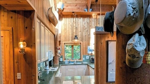 A wooden interior with a kitchen area, wooden walls, and a window.